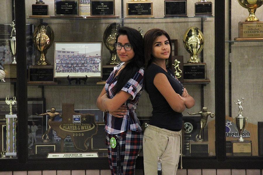 Freshmen team receivers Sophia and Ciltali in front of the football trophy section.