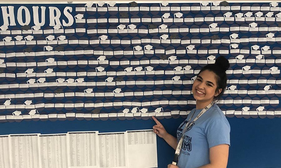Senior Danielle Cervin points at her name on the hours wall. She has her 8 required hours and is going to turn in more.