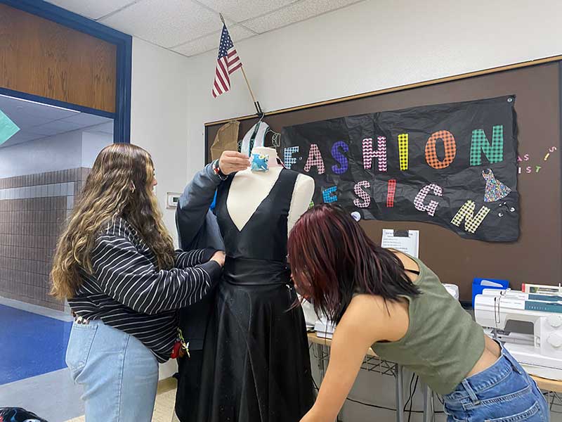 Seniors in 5th, Diana, Noelle, Iris work on their v-neck, circle skirt gown for the TSA fashion competition.